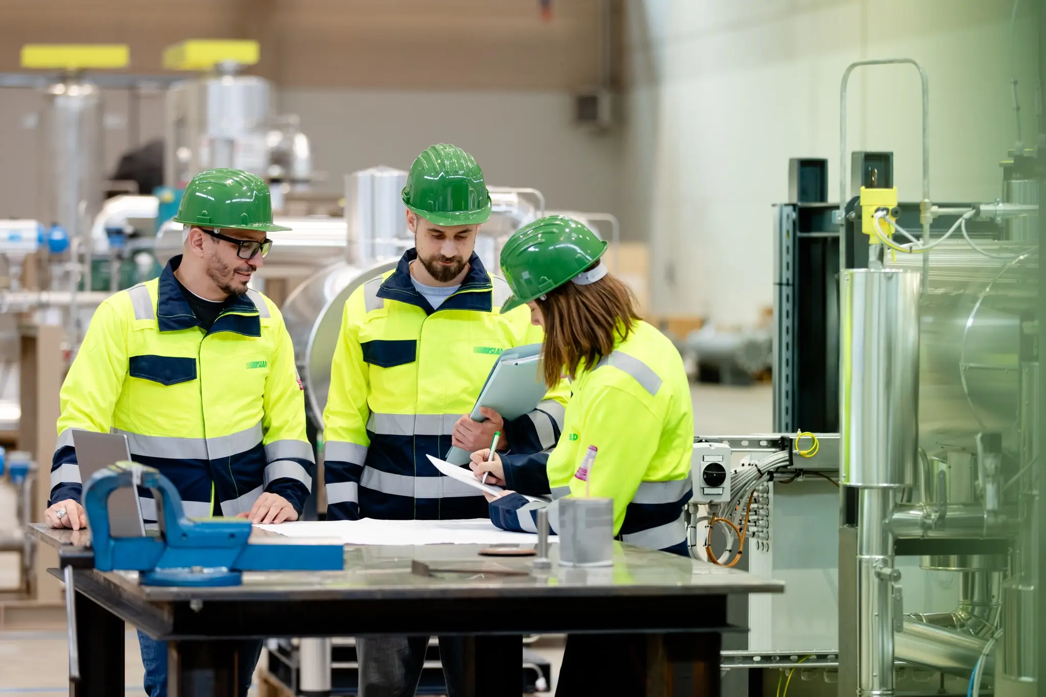 SIAD employees wearing yellow safety helmets and vests working on a project inside the plant construction hall