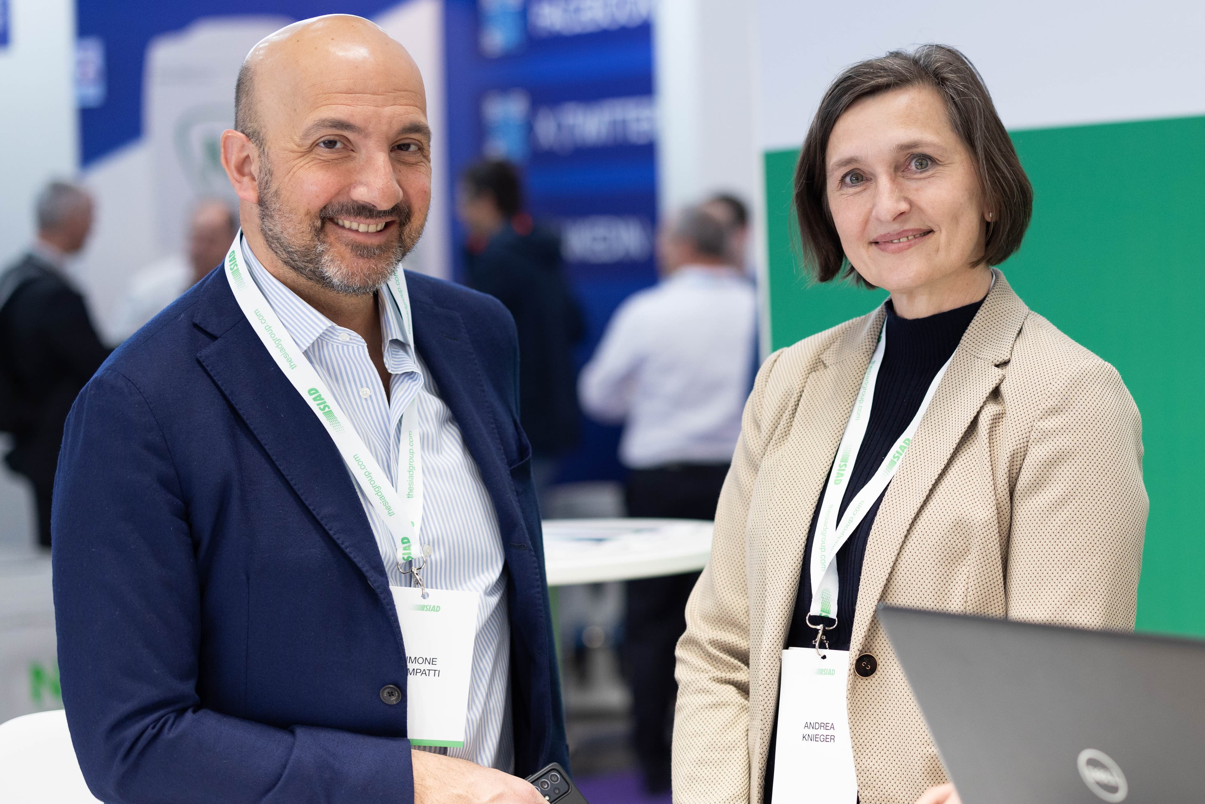 Two professionals wearing event badges networking at a business exhibition booth