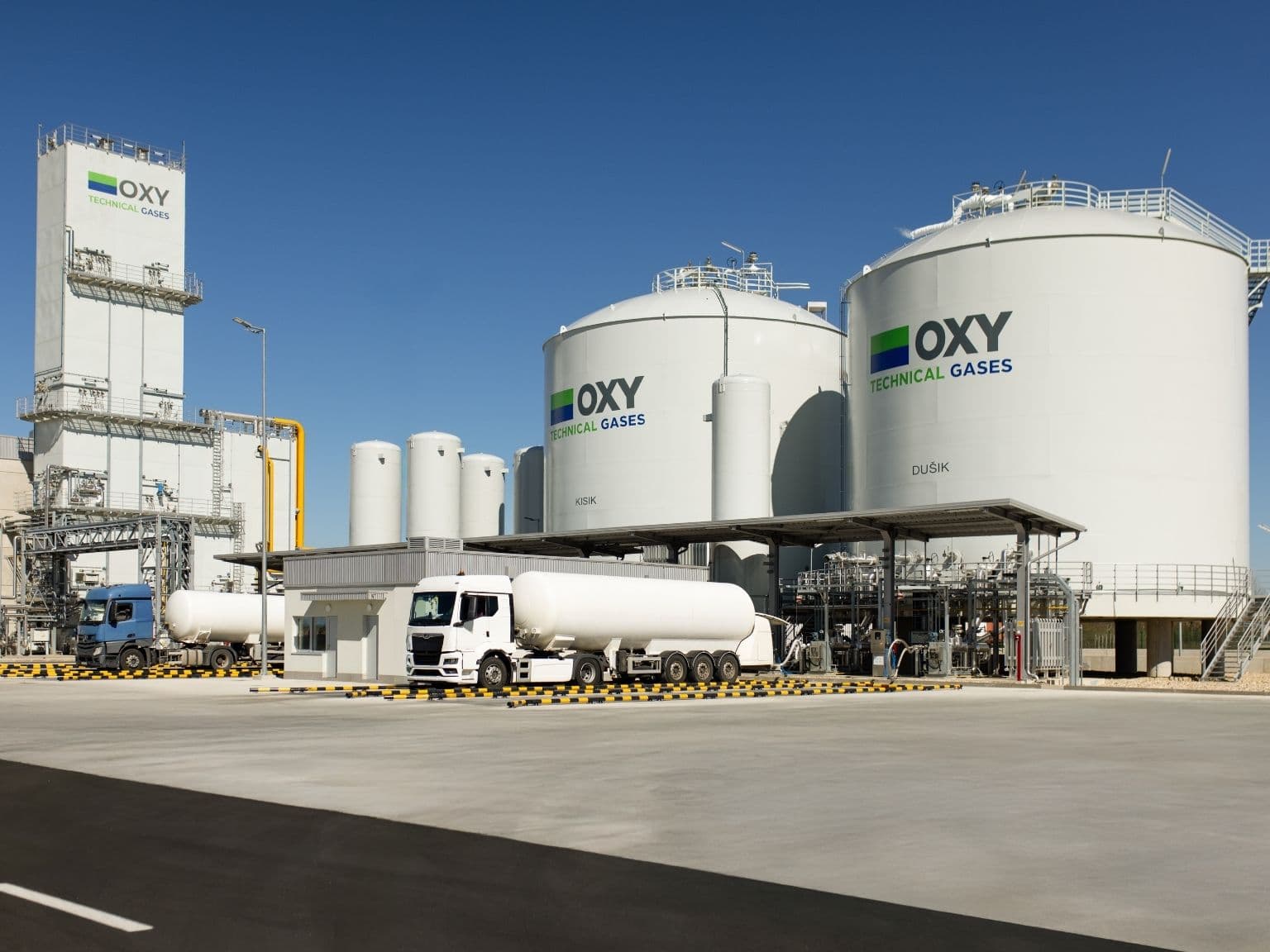 OXY Technical Gases facility with large cylindrical storage tanks, pipelines, and tanker truck on site