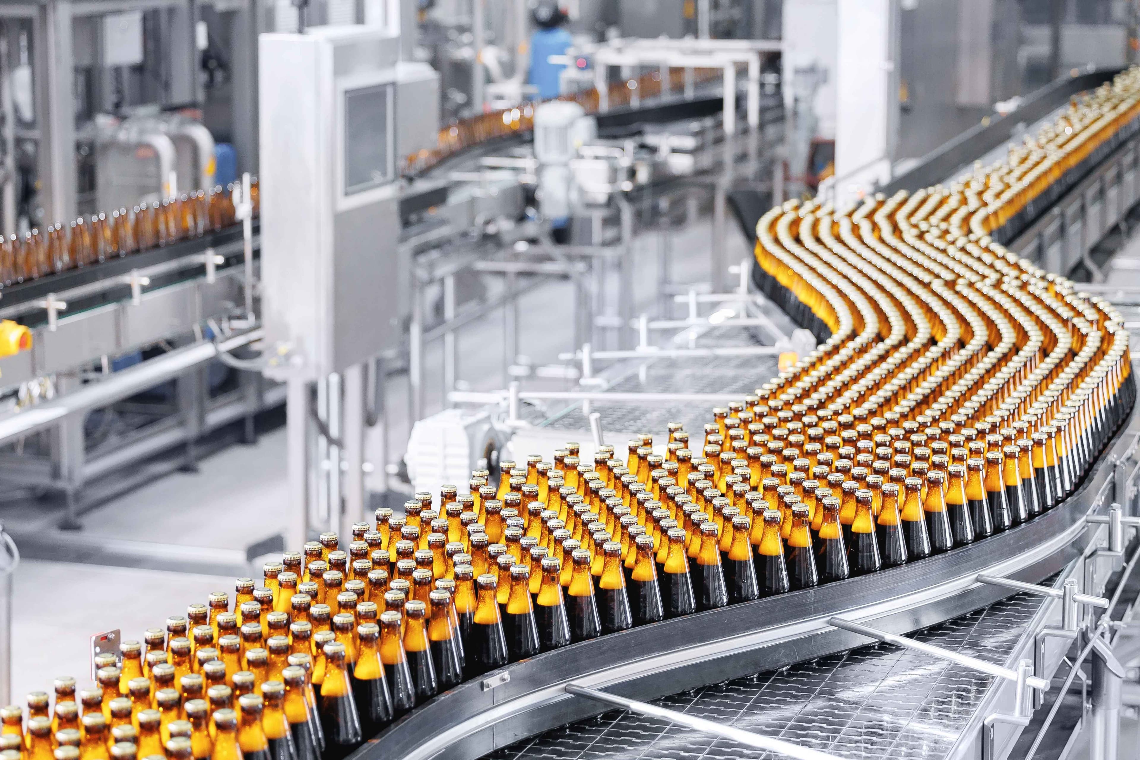 Brown glass beer bottles on conveyor belt Automated brewery industry manufacturing with sunlight.