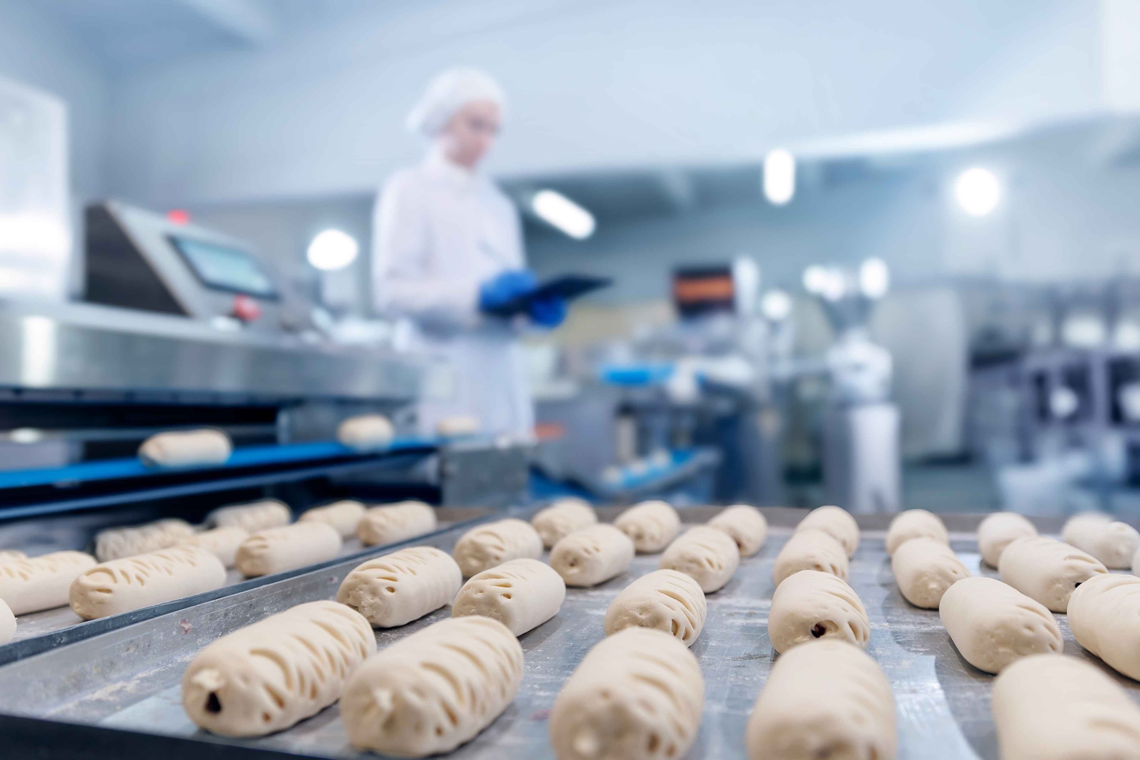 Confectionery production, female technologist ensures quality in puff pastry bun manufacturing process.
