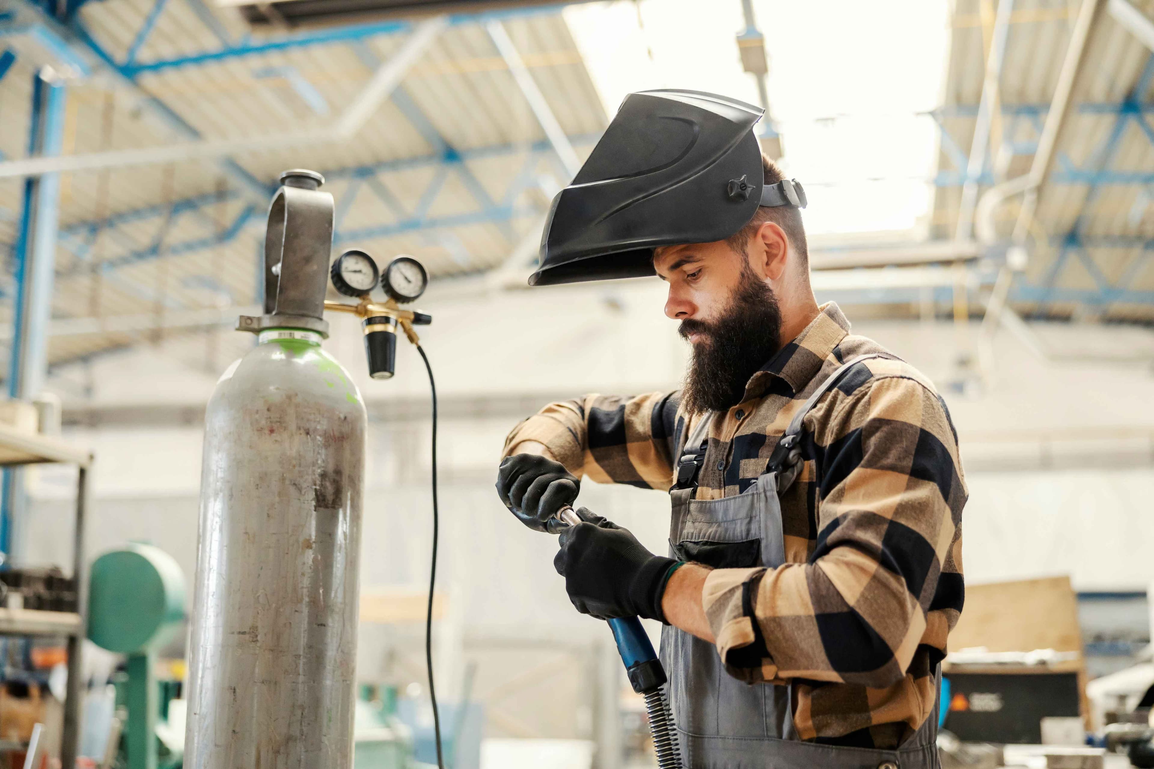 A heavy industry worker preparing welder for work in facility.