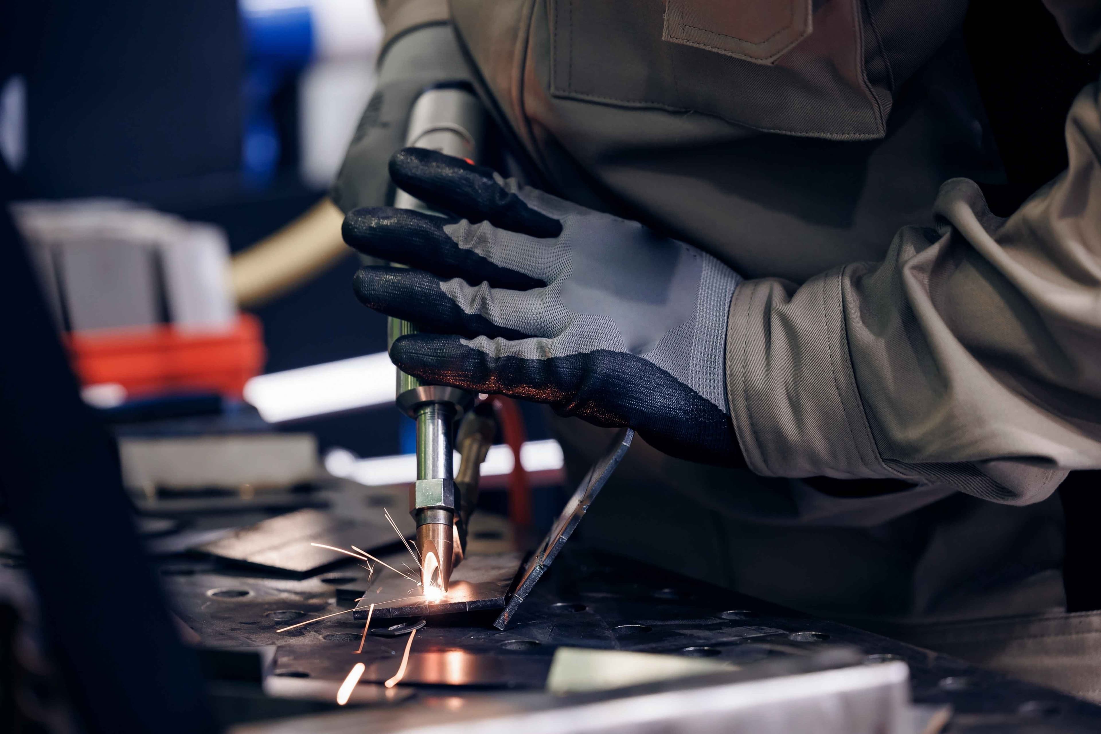 Worker use weld metal welding machine in workshop, blue sparks.