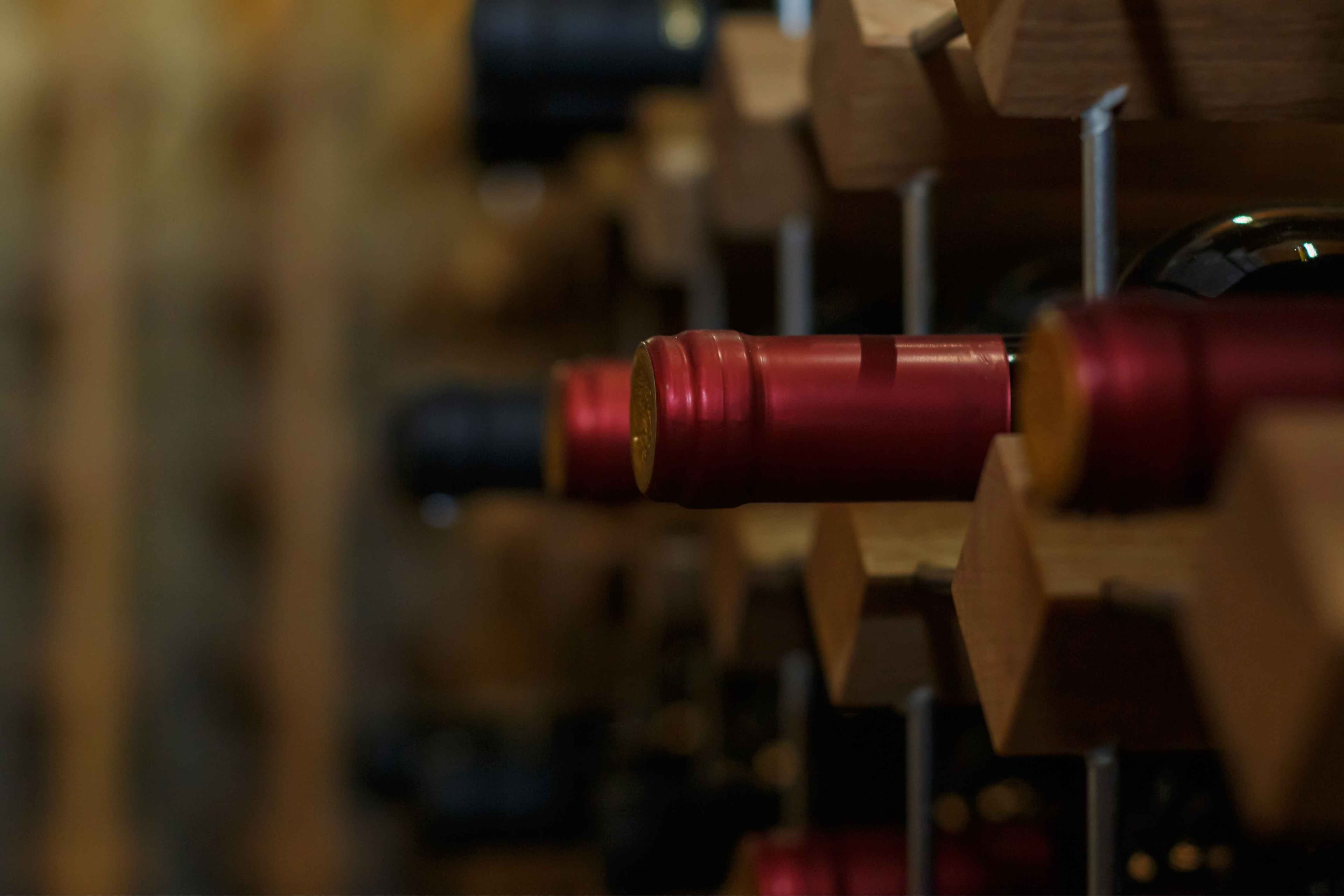 Bottiglie di vino rosso disposte ordinatamente in una griglia di legno, che mostrano la bellezza della raccolta e dello stoccaggio del vino.