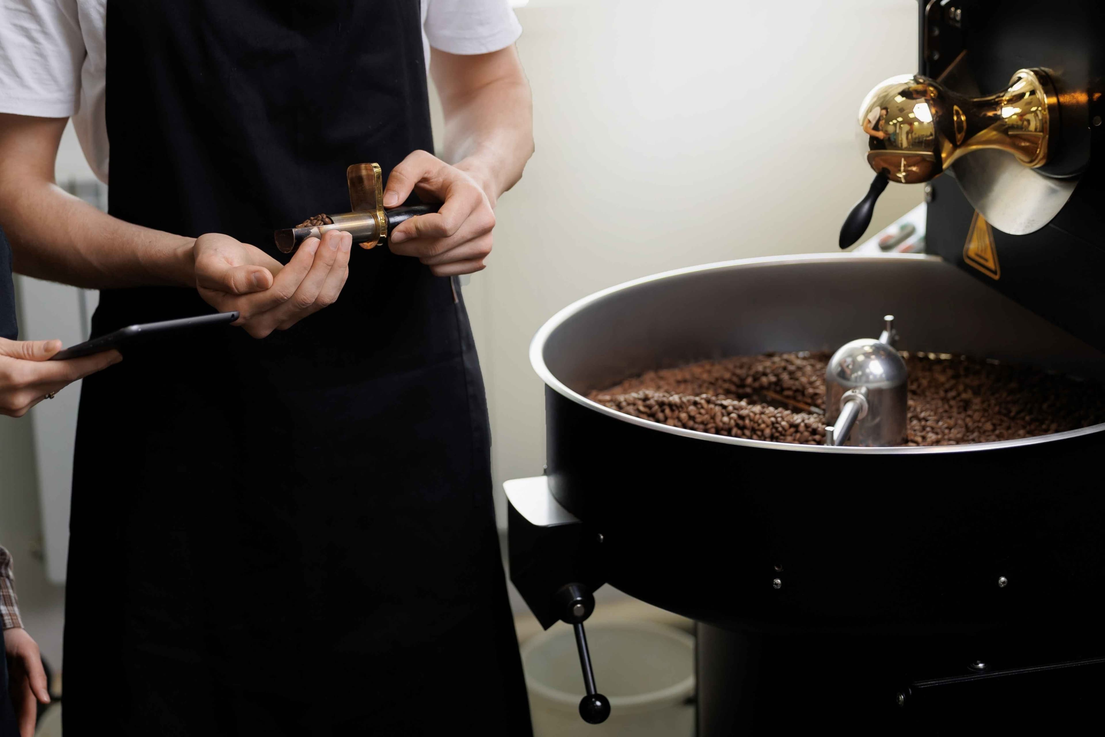 Le operazioni della fabbrica di caffè, i lavoratori maschi e femmine che controllano la qualità e il processo di torrefazione.